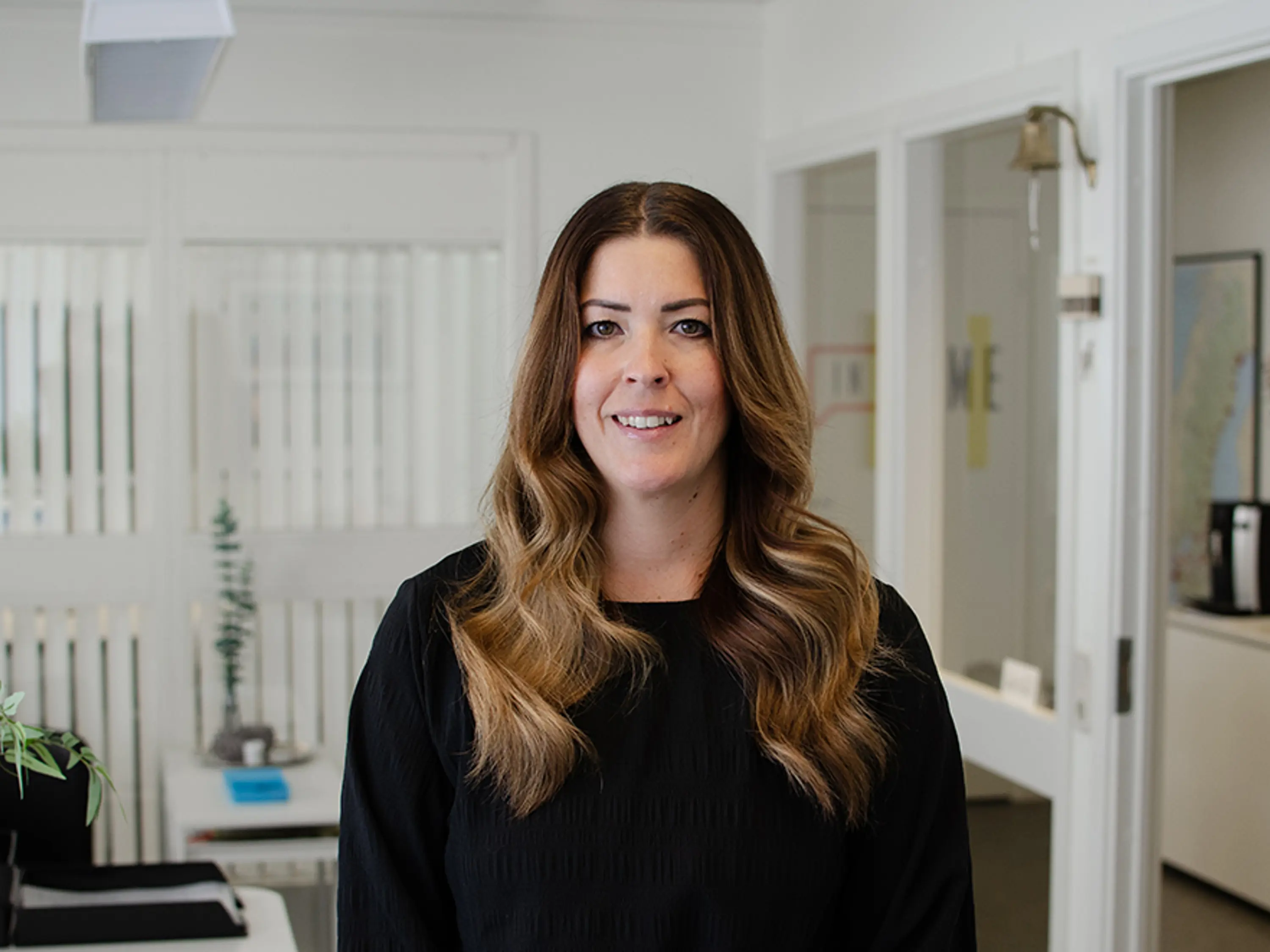 Kvinna med brunt hår som står inne i ett kontor